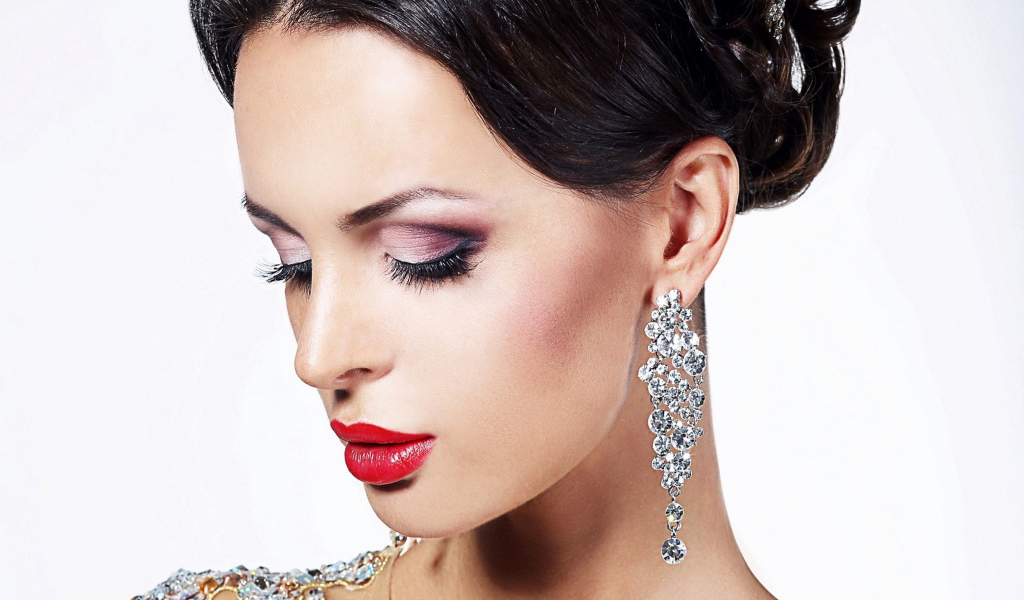 Красивая брюнетка в дорогих украшениях на белом фоне