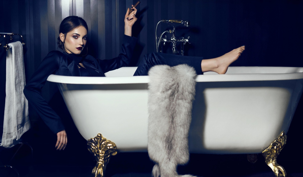 Красивая брюнетка с сигарой  в руках лежит в ванной