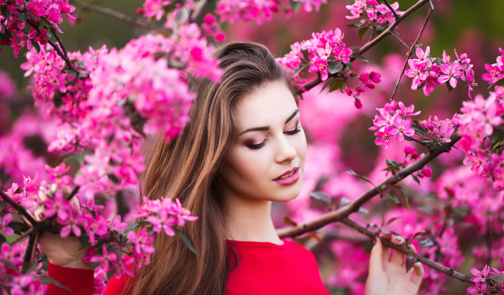 Красивая нежная шатенка у цветущей розовыми цветами ветки