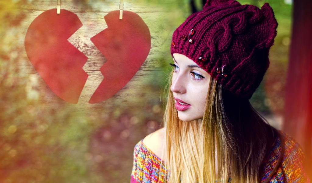 Красивая девушка в вязаной шапке на фоне разбитого сердца
