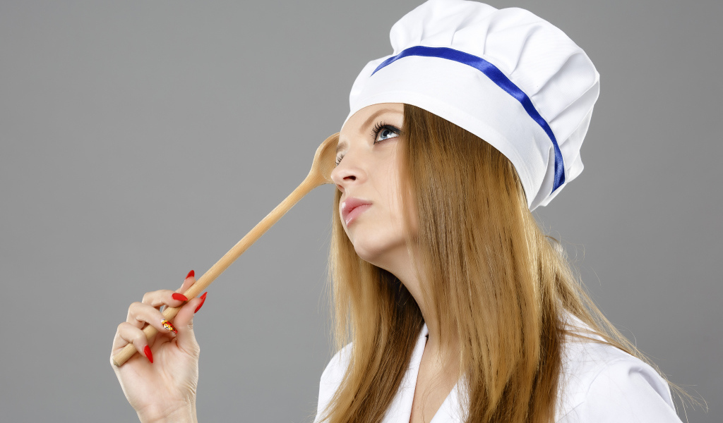 Красивая девушка в костюме повара на сером фоне