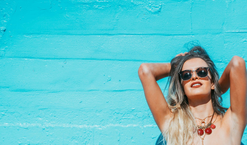 Красивая девушка в солнечных очках загорает на солнце летом