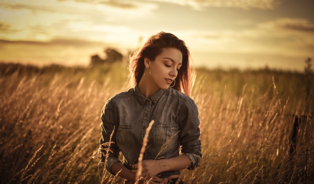 Красивая девушка на поле с колосками на фоне солнца
