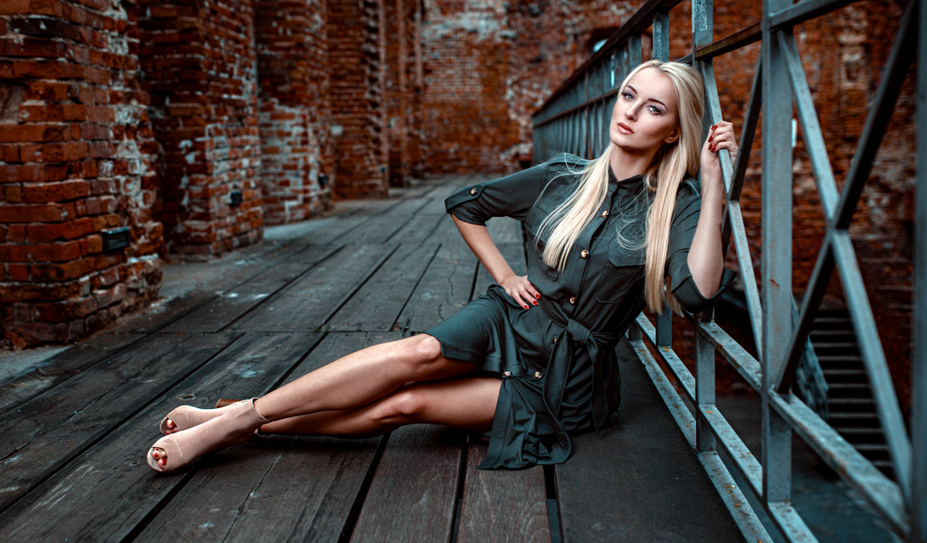 Красивая девушка сидит на деревянном полу