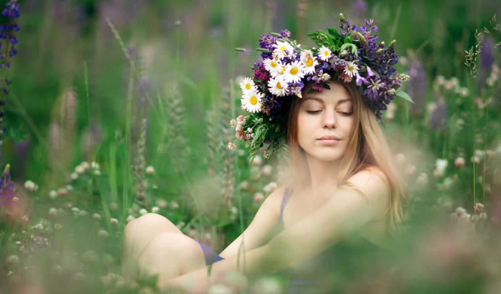 Красивая девушка с венком из полевых цветов на голове летом 