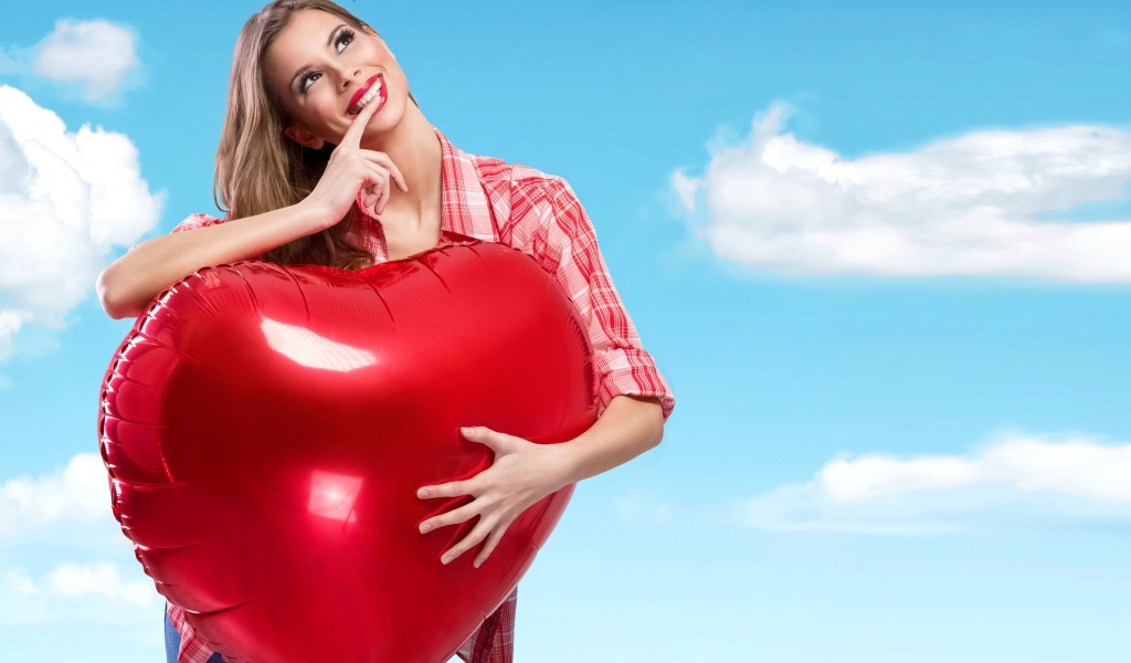 Красивая девушка с большим воздушным шаром в форме сердца на фоне неба