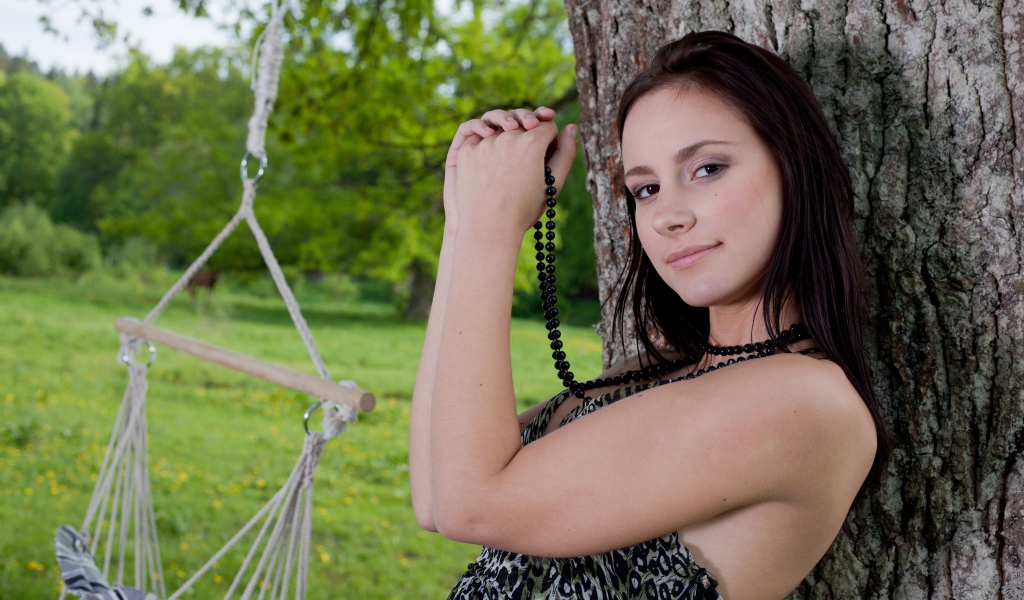 Красивая девушка с черными бусами под деревом