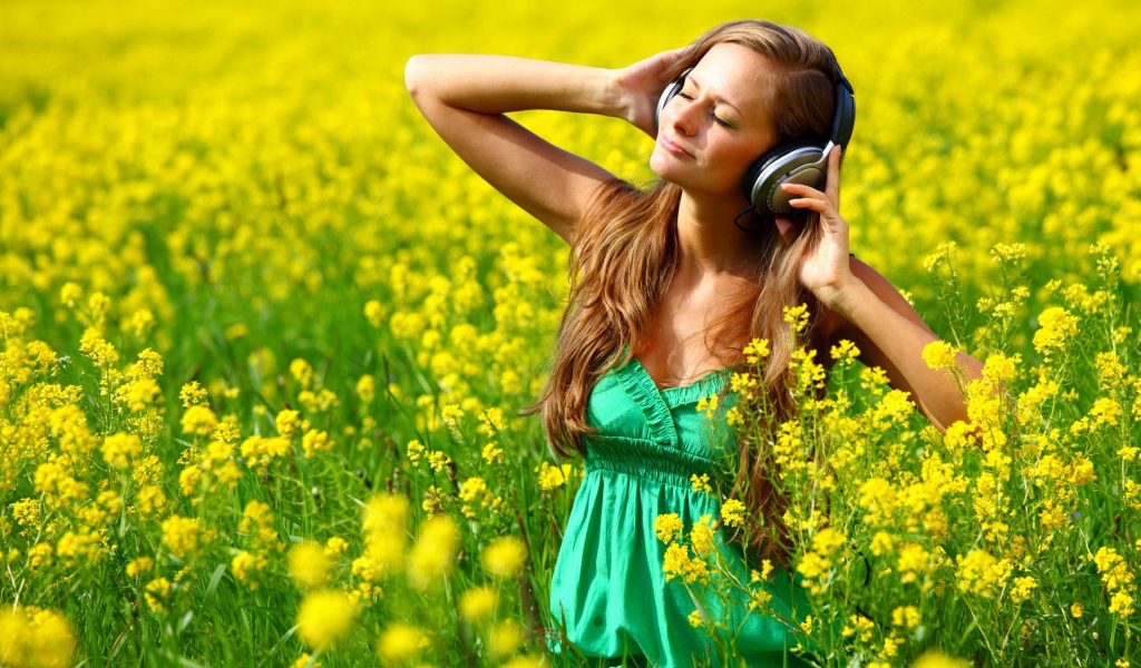 Красивая девушка в наушниках среди желтых цветов