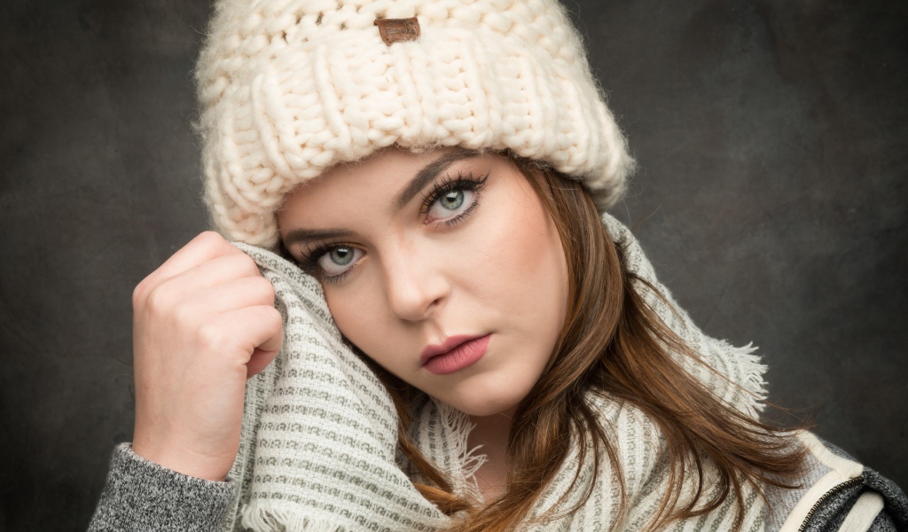 Красивая зеленоглазая девушка в белой вязаной шапке с шарфом