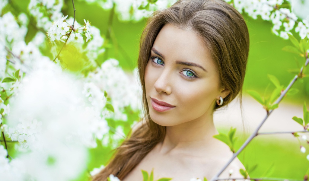 Красивая зеленоглазая девушка у цветущей вишни 