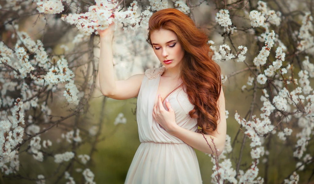 Красивая рыжеволосая девушка у цветущего дерева абрикоса 
