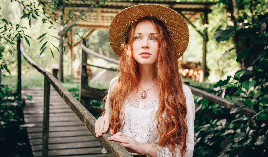 Красивая рыжеволосая девушка в соломенной шляпе