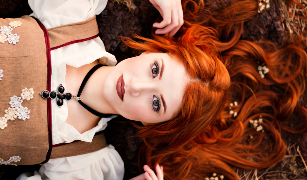 Красивая рыжеволосая девушка лежит на земле 