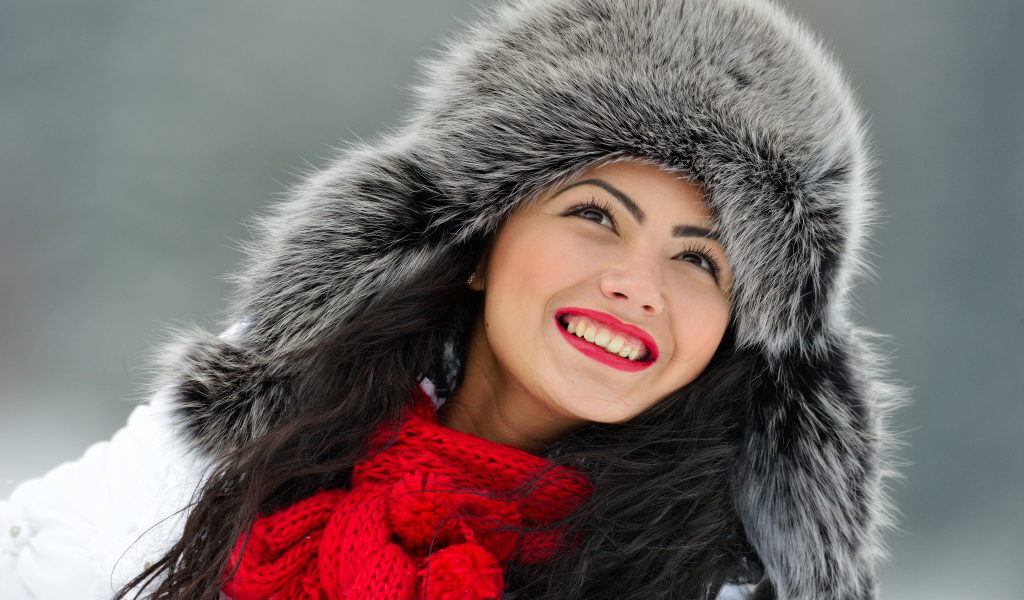 Красивая улыбающаяся брюнетка в теплой зимней шапке