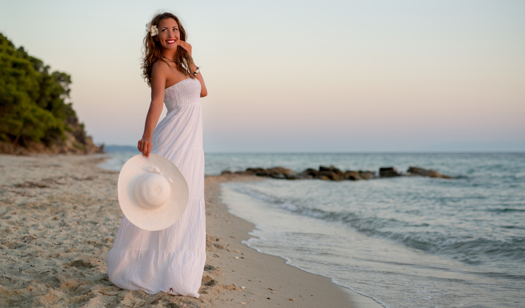 Красивая улыбающаяся девушка в белом платье на побережье