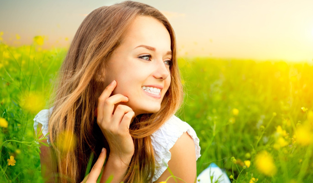 Красивая улыбающаяся молодая девушка лежит в зеленой траве
