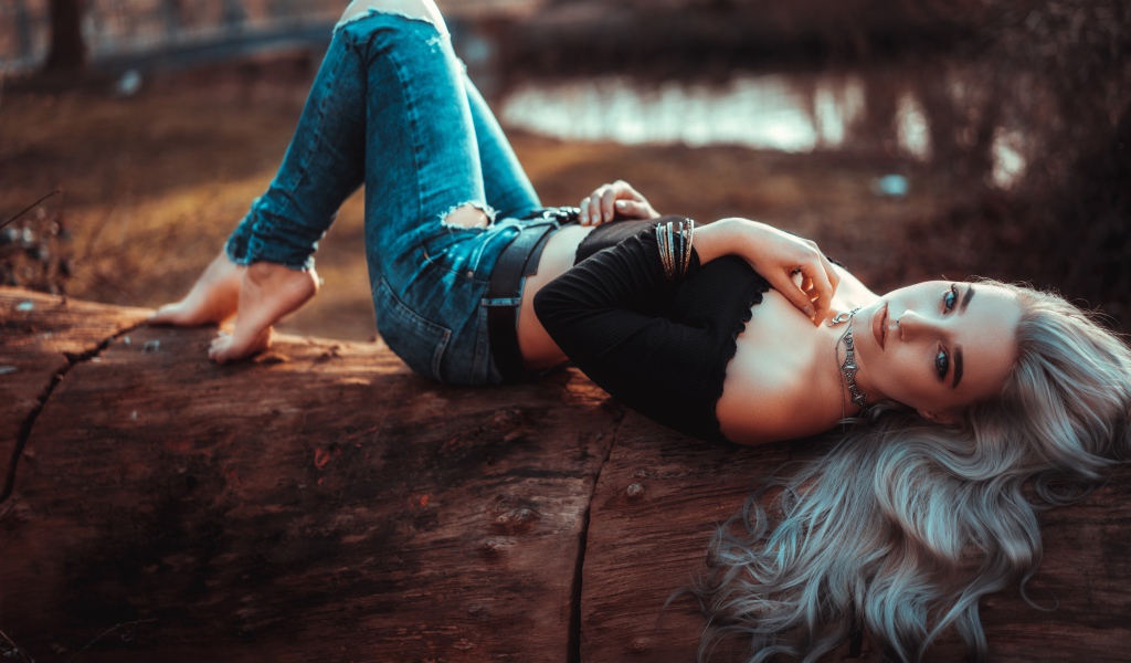 Красивая молодая блондинка лежит на сухом дереве