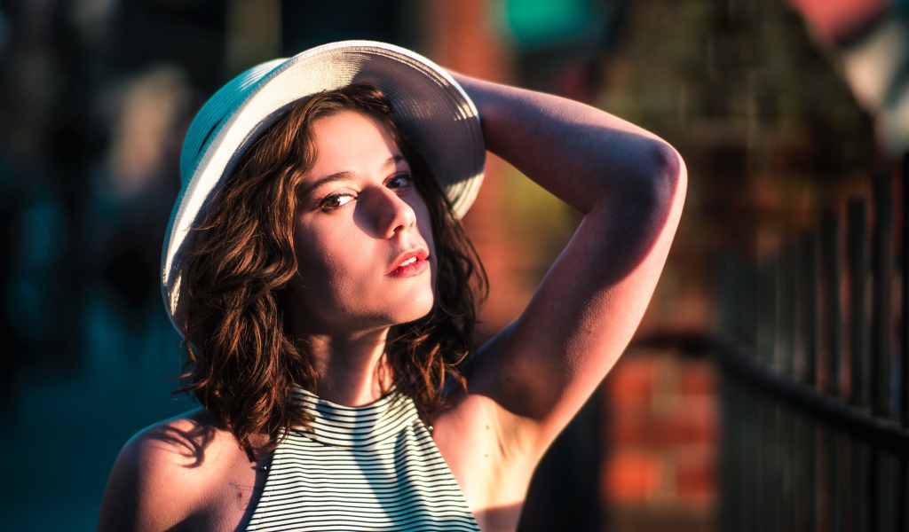 Красивая молодая девушка в белой шляпе в свете солнца