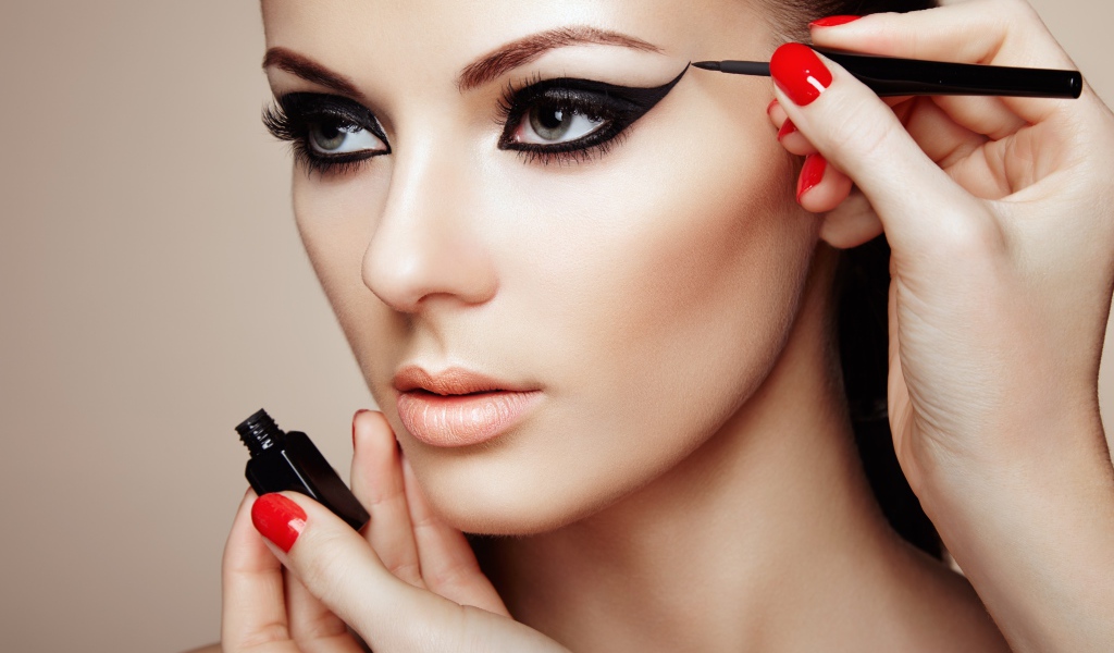 Красивой молодой девушке модели делают макияж глаз