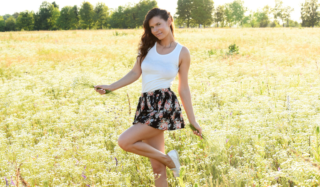 Красивая молодая девушка на поле с белыми ромашками