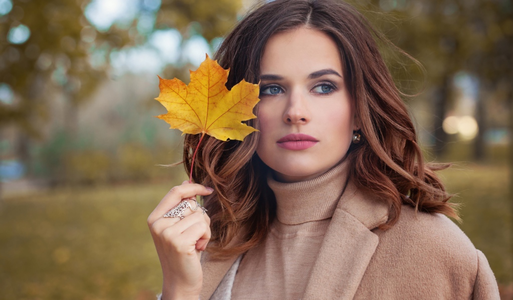 Красивая молодая девушка шатенка с желтым листом в руке