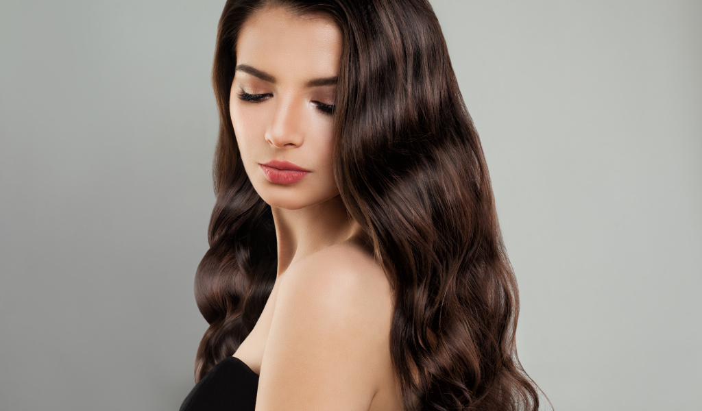 Красивая молодая длинноволосая девушка брюнетка на сером фоне