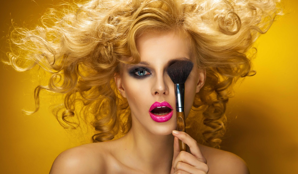 Блондинка с ярким макияжем с кистью у лица