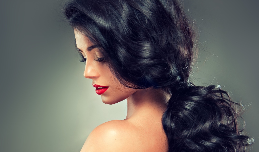 Девушка брюнетка с красивыми волосами на сером фоне