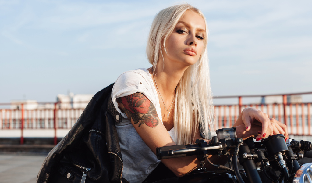 Брутальная блондинка с татуировкой на руке на мотоцикле 