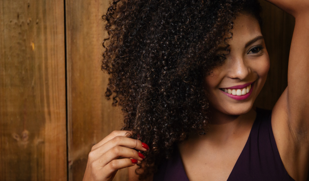 Кучерявая темнокожая девушка с красивой улыбкой 