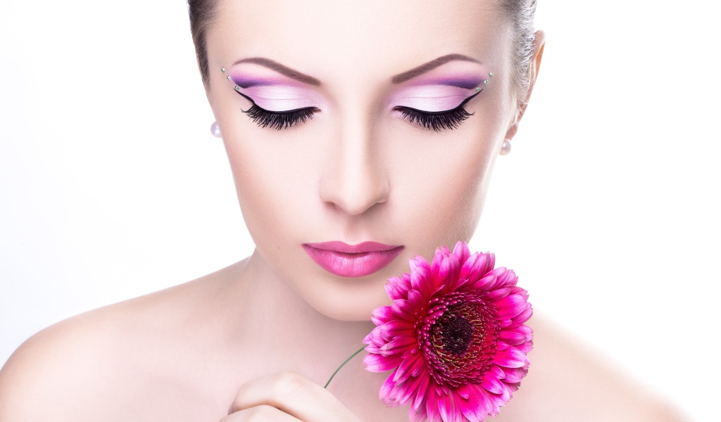 Нежная девушка с розовым цветком герберы на белом фоне