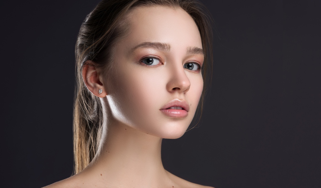 Нежная настоящая девушка шатенка на сером фоне