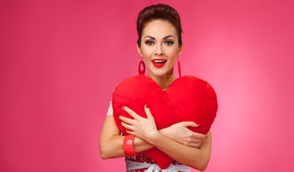 Счастливая девушка с большим красным сердцем на розовом фоне
