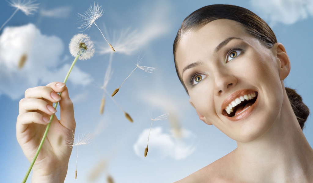 Счастливая девушка с одуванчиком в руке 