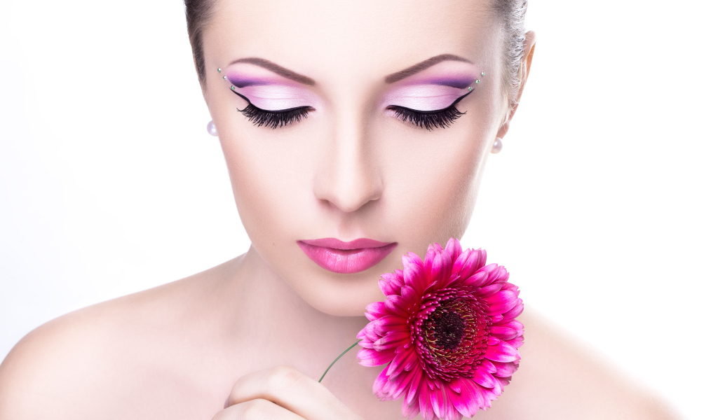 Девушка модель с нежным макияжем с розовым цветком герберы в руке