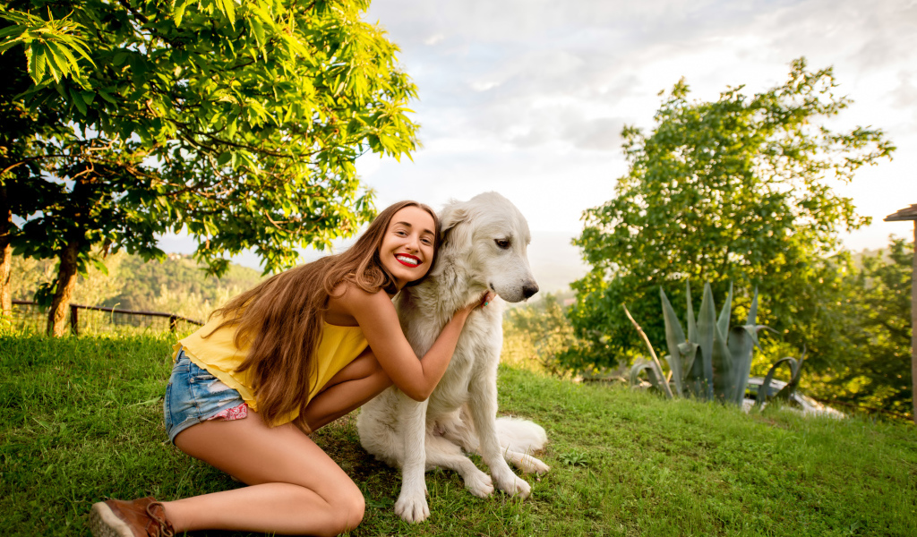 Улыбающаяся шатенка с золотистым ретривером на зеленой траве летом