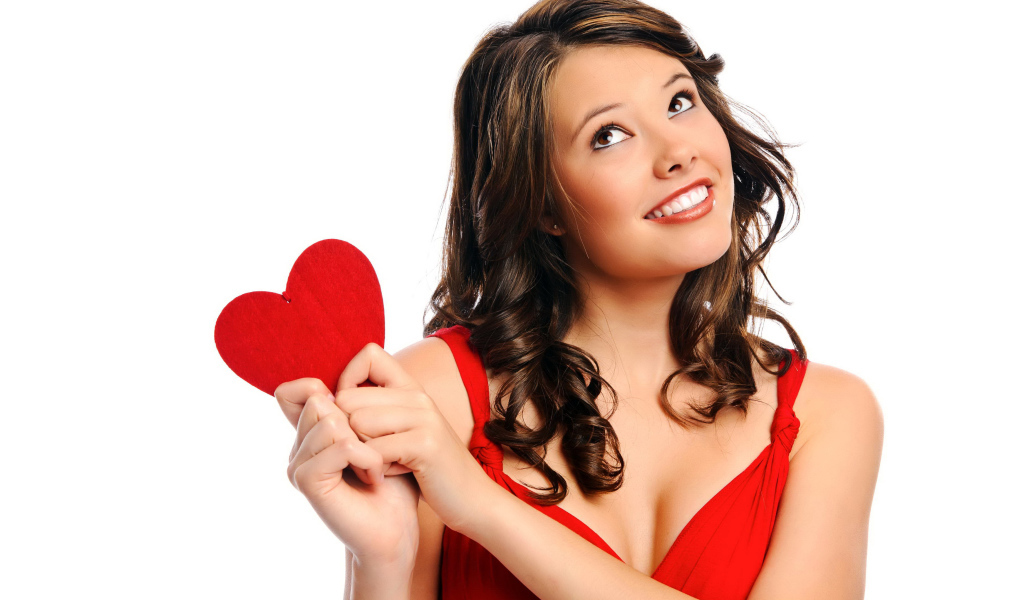 Улыбающаяся девушка с красным сердечком в руках на белом фоне