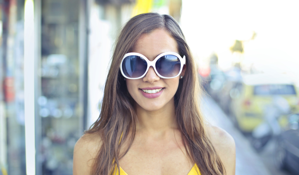 Улыбающаяся молодая девушка в солнечных очках 