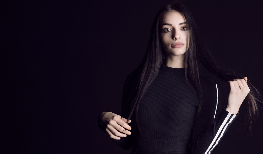 Эффектная брюнетка в черном наряде на черном фоне