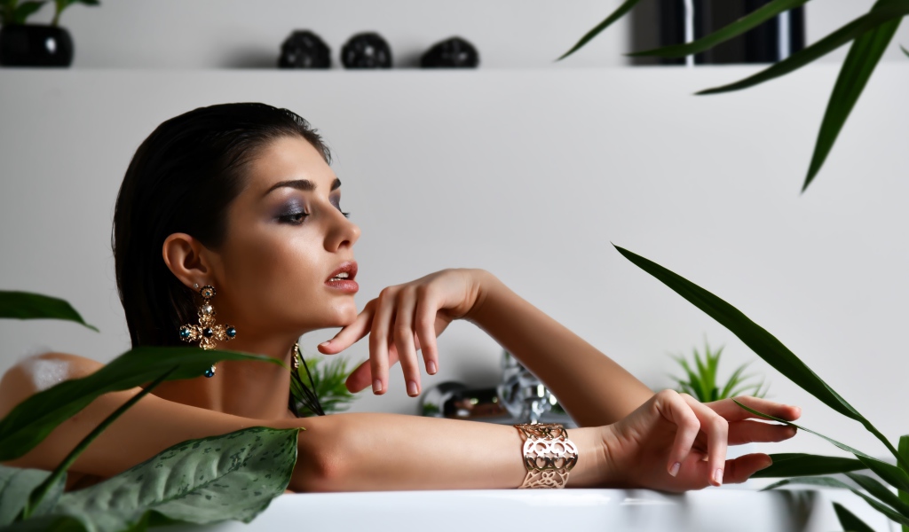 Девушка в дорогих украшения лежит в ванной