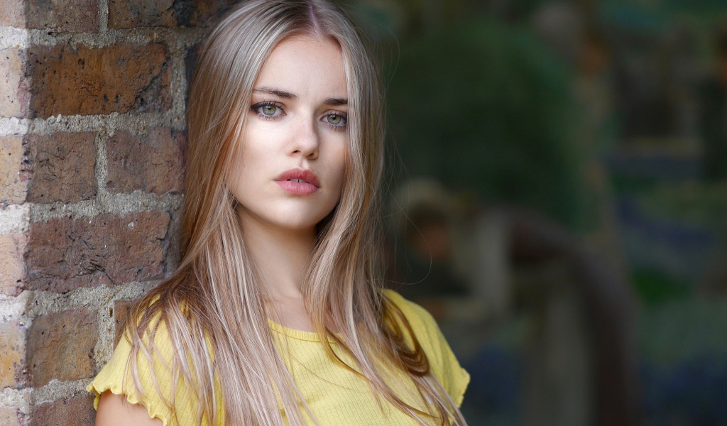 Грустный взгляд красивой светловолосой девушки у стены
