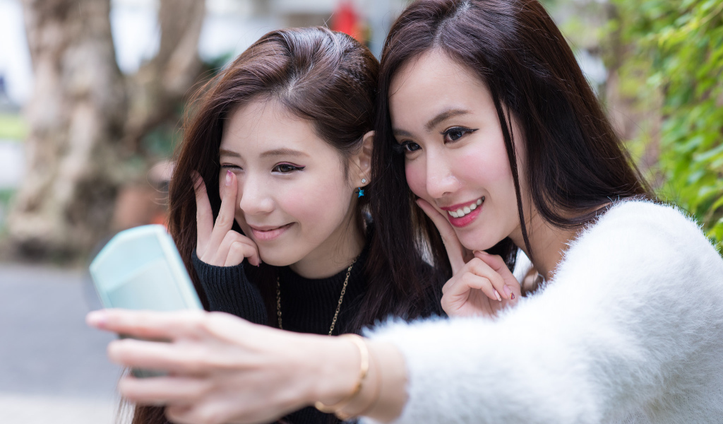 Две девушки азиатки делают селфи