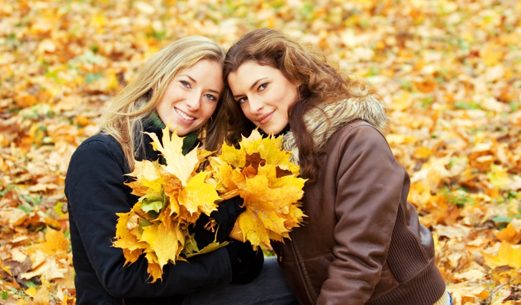 Две красивые девушки с желтыми листьями в руках