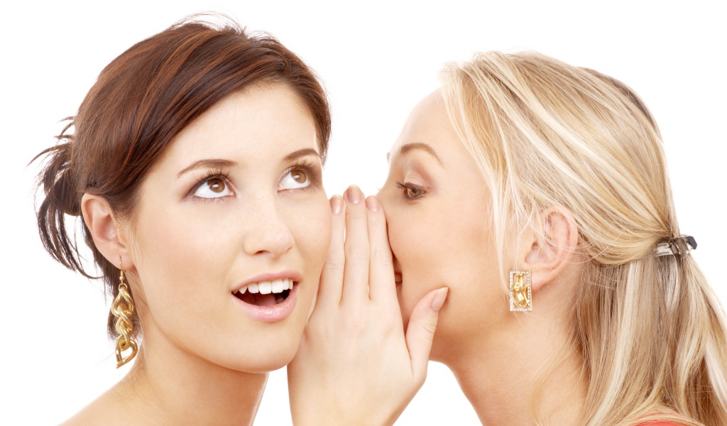 Две подруги делятся секретами на белом фоне 