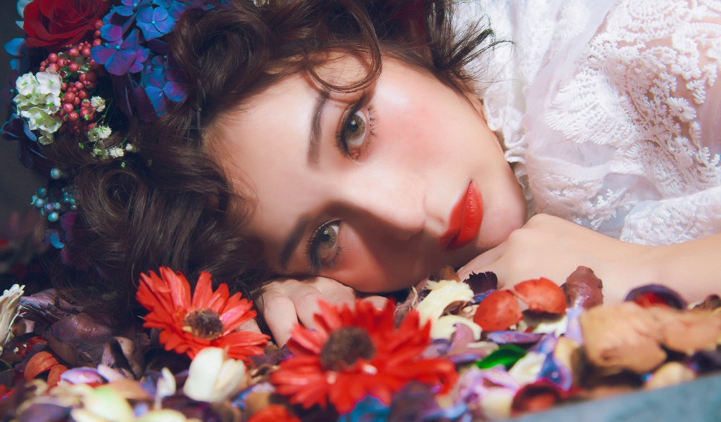 Молодая красивая девушка лежит цветами в волосах
