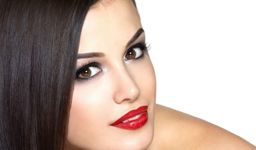 Молодая кареглазая брюнетка с красными губами на белом фоне