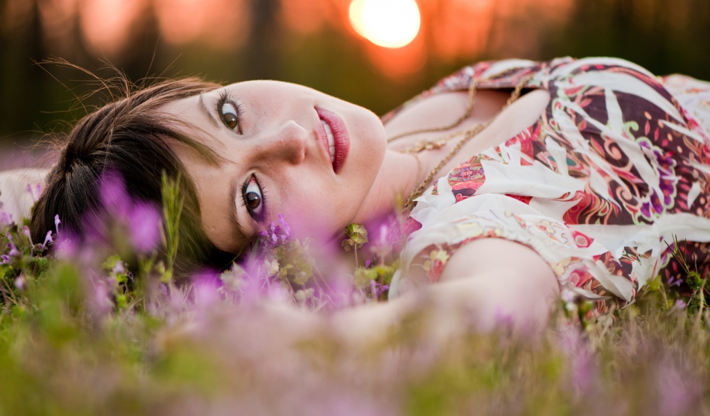 Молодая кареглазая девушка лежит на траве