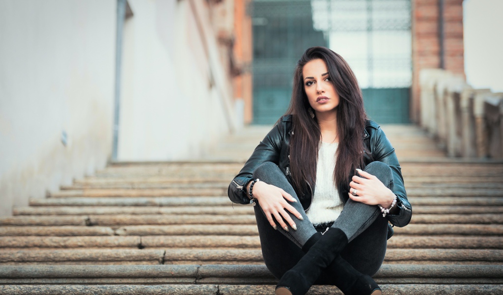 Молодая брюнетка сидит на ступеньках