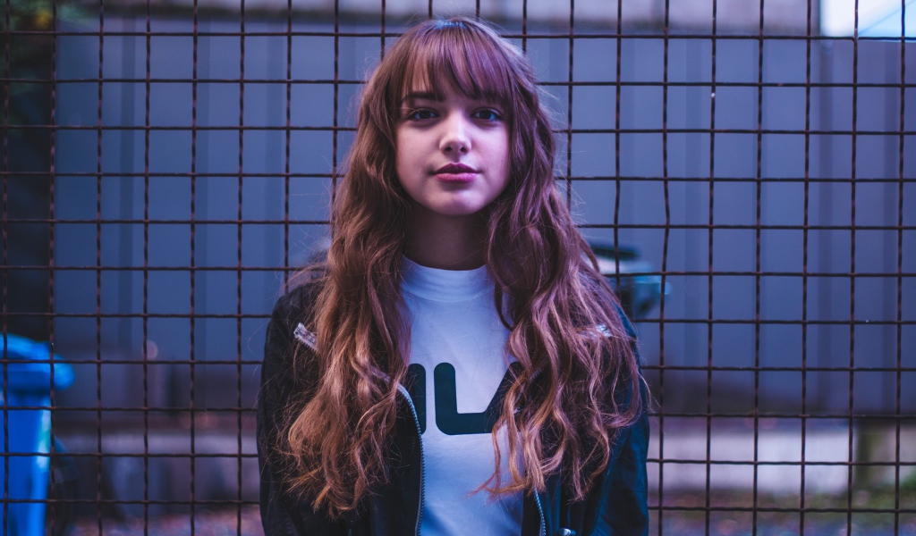 Молодая девушка на фоне железной сетки