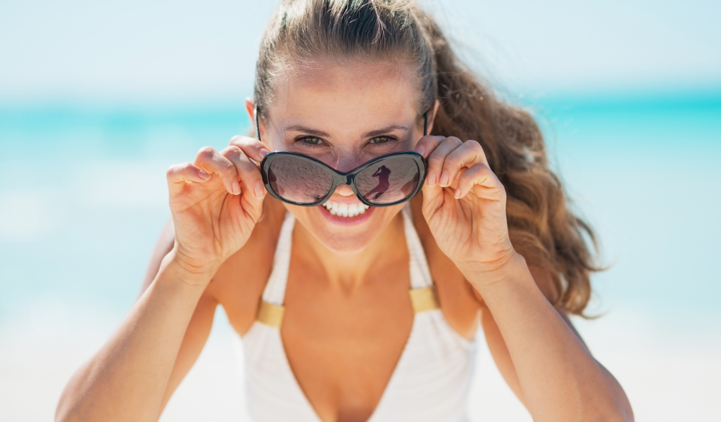 Молодая улыбающаяся девушка в солнечных очках 